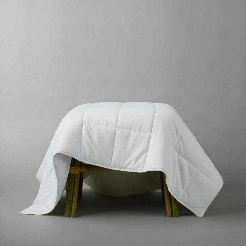White quilt draped over a wooden stool on a gray background